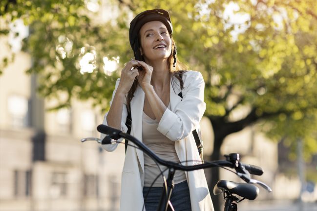 Donna con casco va al lavoro in bici