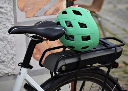 Bicicletta elettrica con casco verde appoggiato sul portapacchi posteriore